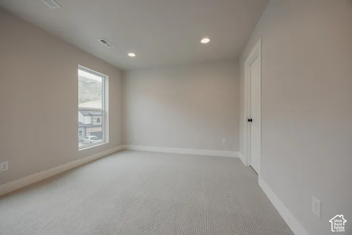 Neutral interior space featuring high-pile carpet, recessed lighting, and a single-panel interior door with matte black hardware