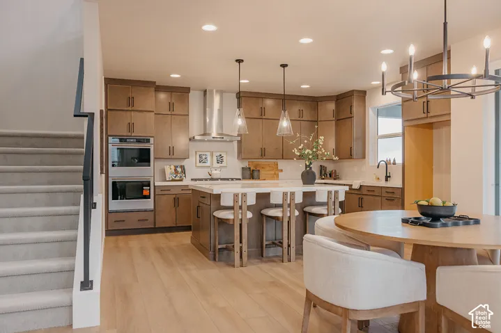Kitchen featuring stained wood cabinetry, quartz countertops, a stainless steel wall oven, recessed lighting, and a tiered kitchen island with pendant lights