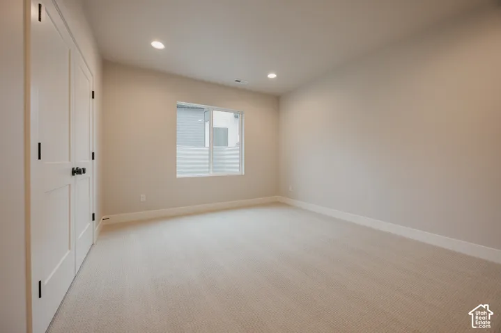 Neutral-toned interior featuring wall-to-wall carpeting, recessed ceiling lighting, a dual-panel closet door with dark hardware, and a single-pane window