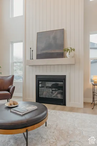 Floor-to-ceiling vertical plank fireplace surround with a light-finish timber mantel and wood-finish flooring
