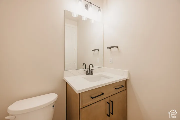 Bathroom featuring a wood-finish vanity with a stone-composite countertop, undermount sink, matte black faucet, and large-scale vanity mirror