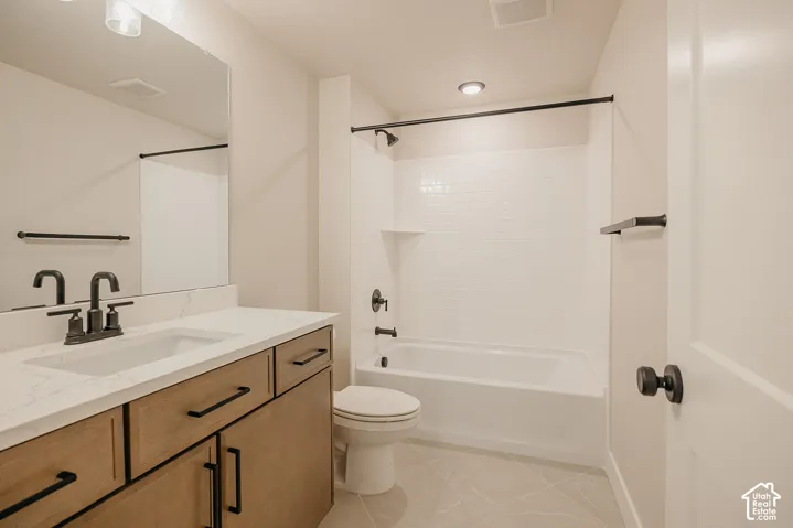 Bathroom featuring a wood-finish vanity with a stone-top integrated sink, matte black hardware, large wall-mounted mirror, and a tub-shower combination with white subway tile surround