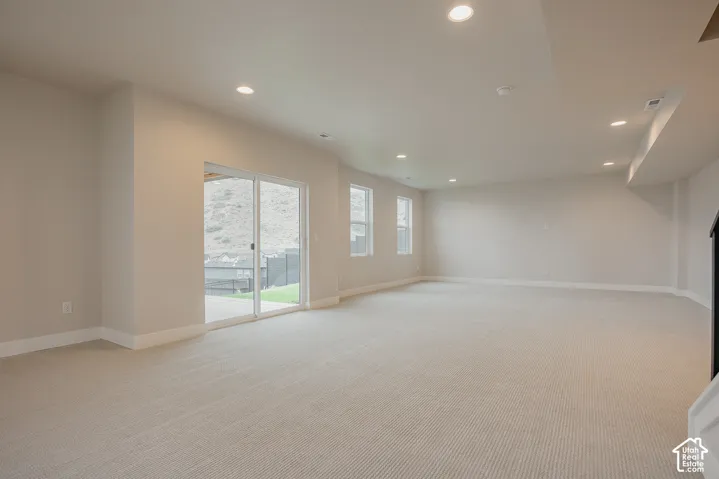 Open interior space featuring neutral wall tones, wall-to-wall carpeting, recessed ceiling lighting, and sliding glass doors