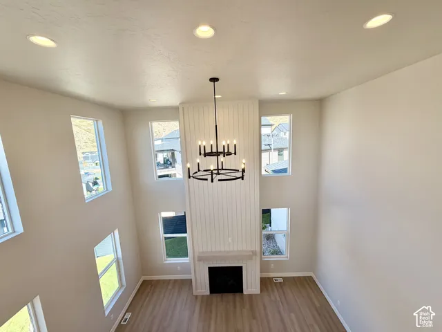 Vaulted ceiling with recessed lighting, floor-to-ceiling fireplace with shiplap accent, and a modern black chandelier