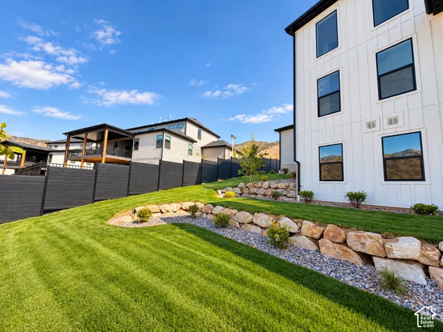 Sloping lawn with rock retaining walls and planted landscape bedsLighting ehanced with ai.