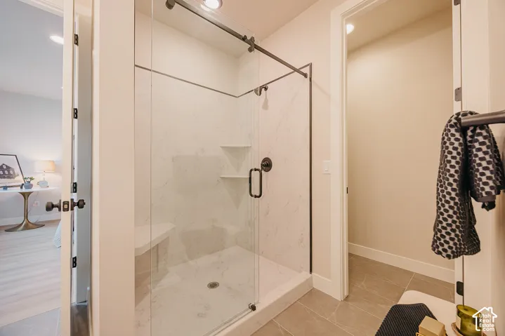 Walk-in shower featuring a frameless glass door, stone-patterned wall surround, built-in shelving, integrated corner bench, and matte black hardware