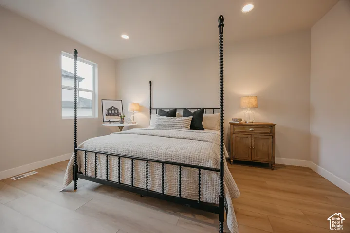 Neutral interior room featuring wood-finish flooring, recessed lighting, and a single-pane window
