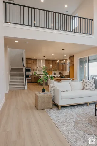 Open-concept interior featuring wood-finish flooring, a vaulted ceiling, matte black metal railing, recessed lighting, and wooden cabinetry