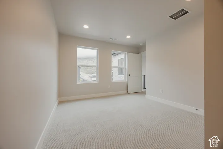 Neutral-toned carpeted flooring, recessed lighting, dual windows, and a shaker-style interior door