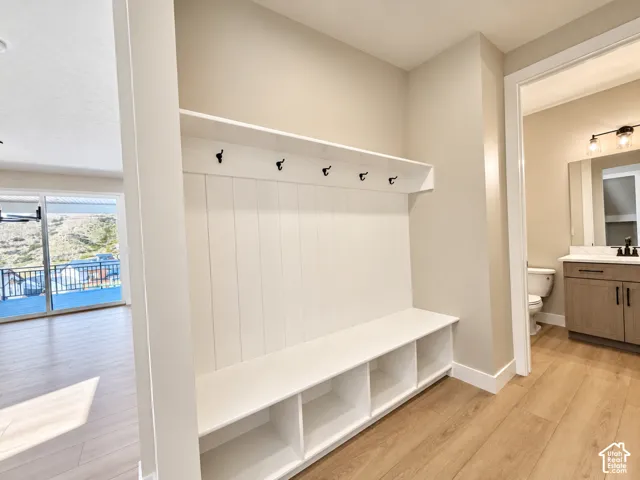Built-in bench with storage cubbies and coat hooks, wood-finish flooring, and a sliding glass door leading to an outdoor deck
