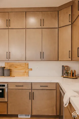 Floor-to-ceiling cabinetry with matte black hardware, stone-finish countertops, and matching slab-style backsplash
