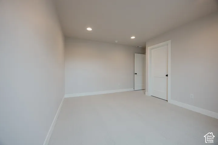 Neutral-toned interior room featuring recessed ceiling lighting, light-colored carpeting, and two-panel doors with matte black hardware