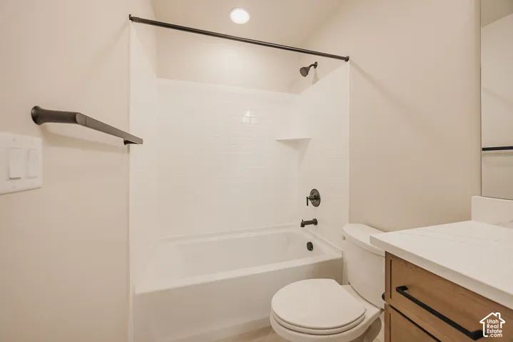 Full bathroom featuring a tub-shower combination with white subway-style tile surround, matte black hardware, light wood-finish vanity with a stone-composite countertop, and a built-in recessed shelf