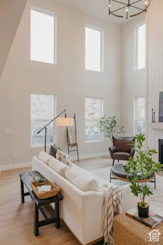 Double-height ceilings, floor-to-ceiling windows, wood-finish flooring, and a fireplace with vertical paneled surround