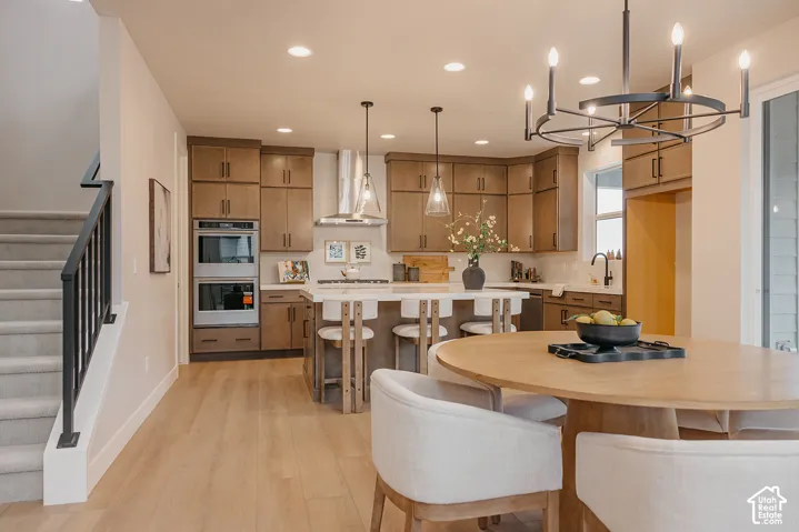 Kitchen featuring full-height wood cabinetry, a central island with quartz countertops, stainless steel built-in double ovens, recessed lighting, and a circular wrought-iron chandelier