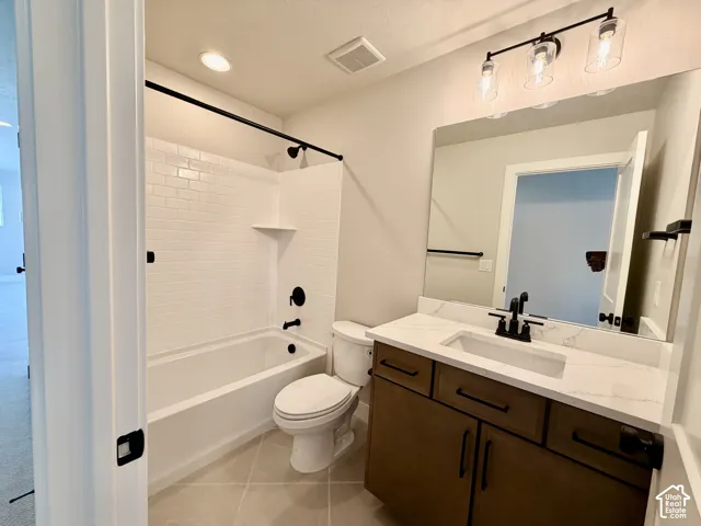 Bathroom featuring a tiled tub/shower combination, dark bronze fixtures, a vanity with a white countertop and integrated sink, and a large wall-mounted mirror
