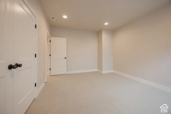 Neutral-toned carpeted flooring, white two-panel interior doors, matte black door hardware, and recessed lighting