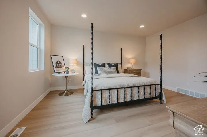 Neutral-toned interior space featuring light-toned wood-finish flooring, recessed ceiling lighting, and a window with white trim