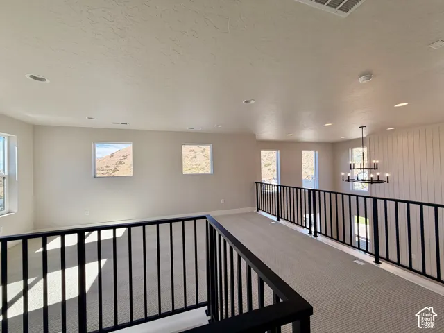 Open loft area featuring neutral-toned carpet, black metal railings, and recessed lighting