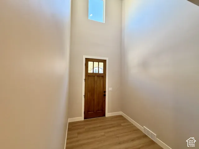 Two-story entryway with a transom window, wood-finish flooring, and a wood entry door with glass paneling