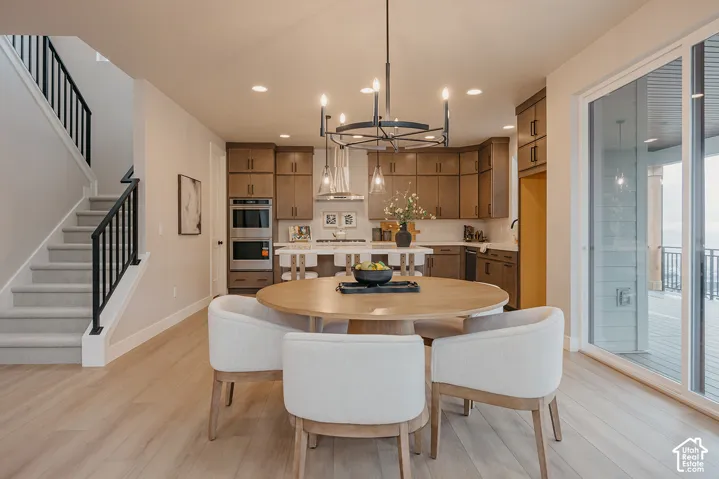 Kitchen featuring custom wood cabinetry, stone countertops, double wall ovens, and a center island with pendant lighting
