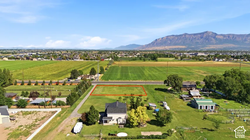 Expansive lot with a mountain backdrop, surrounded by agricultural fields and residential areas