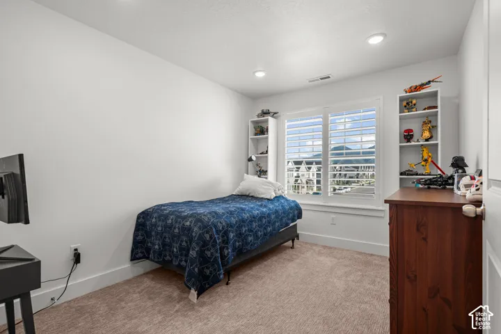 Carpeted room with recessed lighting and a window featuring white plantation shutters
