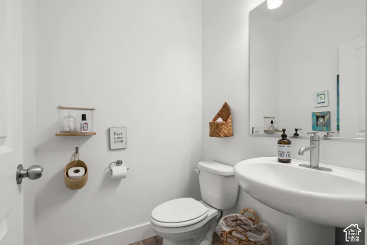 Pedestal sink with a single-handle faucet, wall-mounted mirror, and a toilet