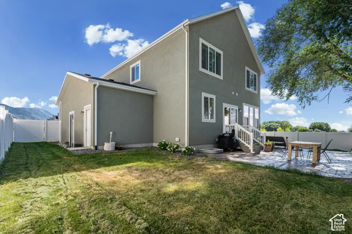Two-story exterior with stucco siding, white-framed windows, and a rear patio