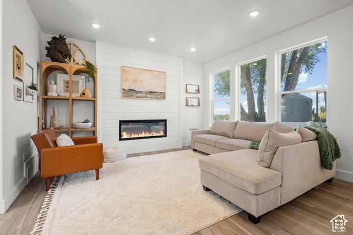 Recessed lighting, wood-finish flooring, shiplap accent wall, built-in fireplace, and multiple windows