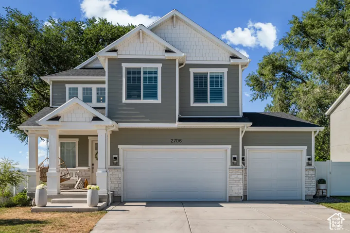 Two-story residence featuring a covered front porch with white columns, a two-car garage, and gray siding with white trim