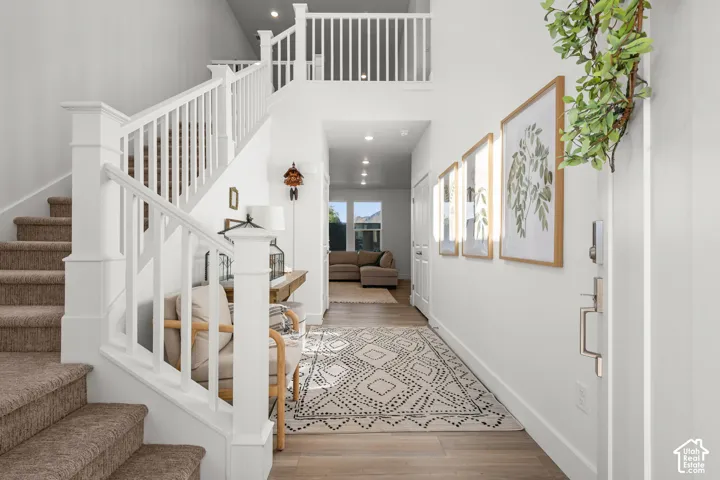 Two-story entryway featuring wood-finish flooring, white painted railings, and recessed lighting
