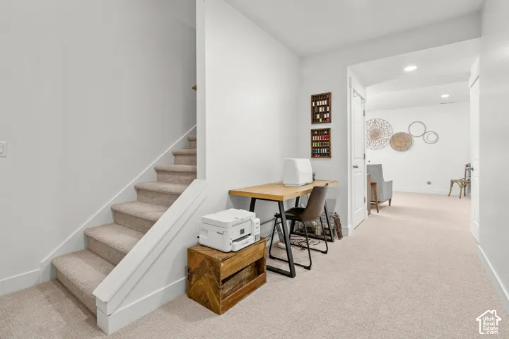 Carpeted staircase with white risers and handrail, neutral carpeting throughout, recessed lighting, and a white interior door