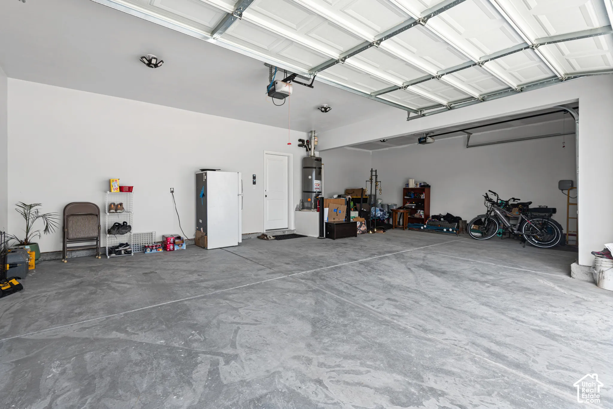 Spacious garage featuring a concrete floor, overhead lighting, and white walls