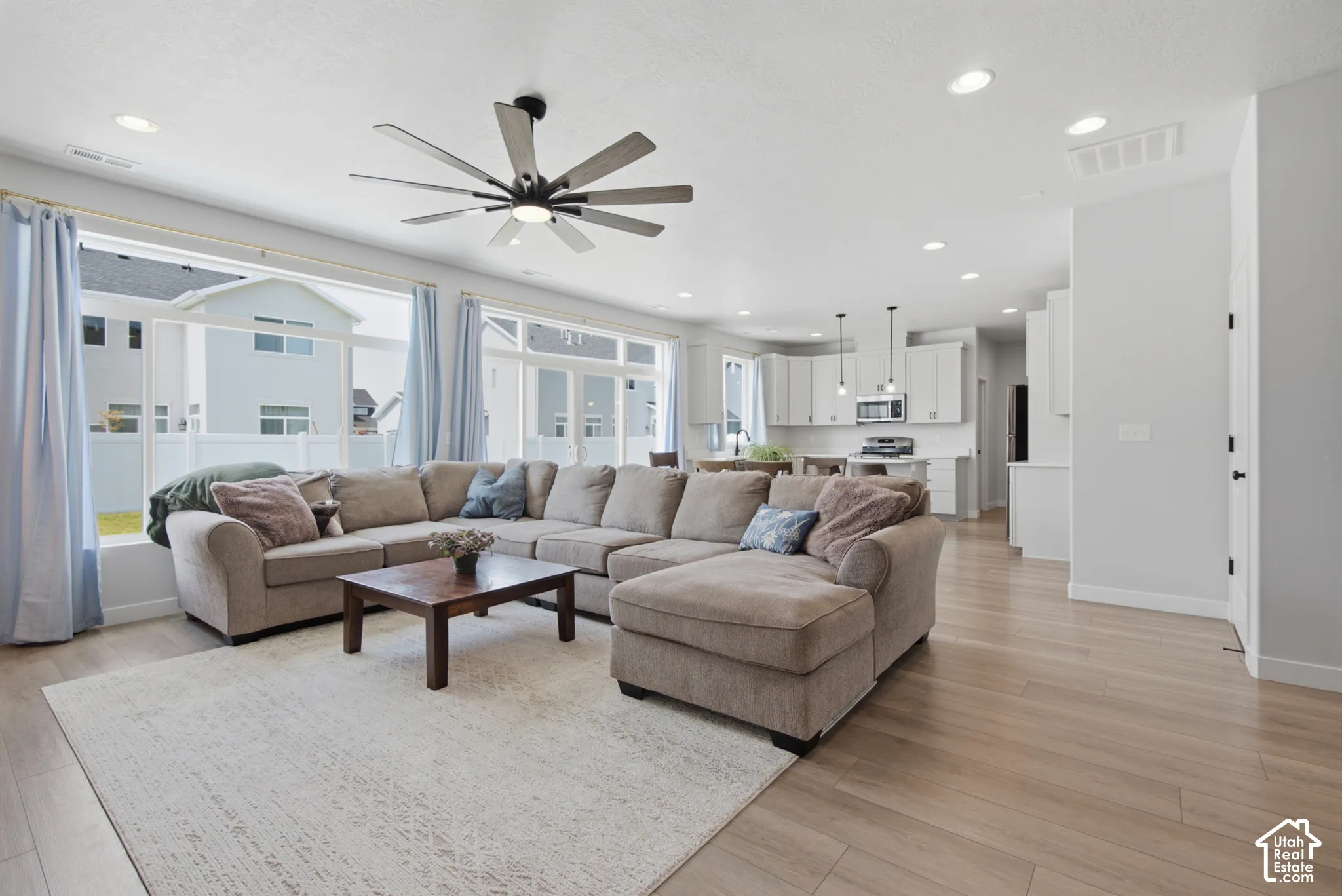 Open-concept living space with wood-finish flooring, recessed lighting, and a modern ceiling fan
