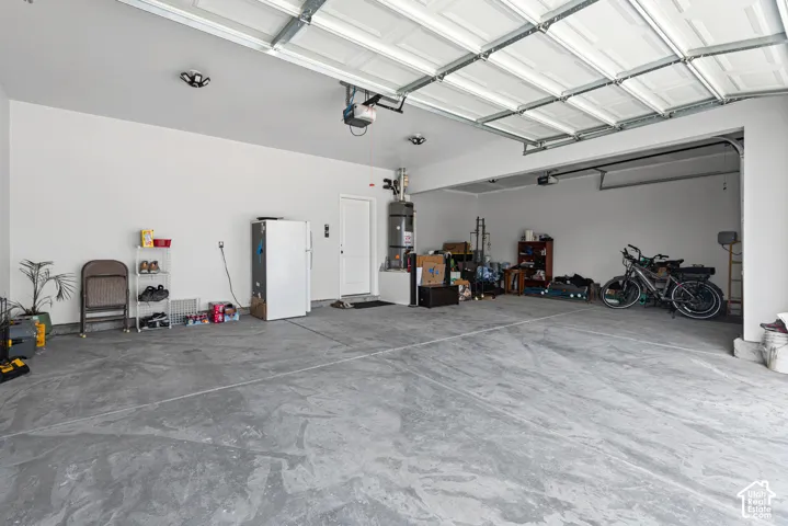 Spacious garage featuring a concrete floor, overhead lighting, and white walls