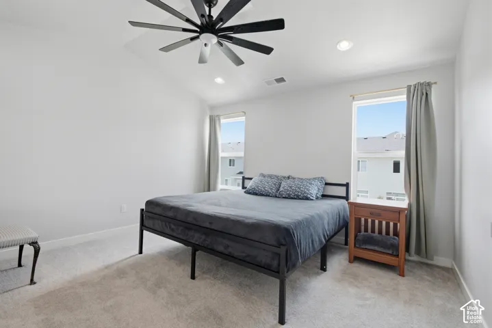 Vaulted ceiling with a ceiling fan, recessed lighting, two windows with window treatments, and wall-to-wall carpeting