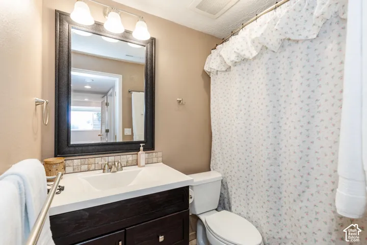 Vanity with integrated sink, dark wood-finish cabinetry, tile backsplash, framed mirror, and brushed nickel fixtures