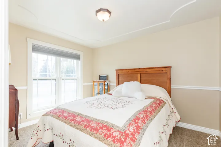 Recessed ceiling detail, crown molding, wall paneling, double-pane window, and carpeted flooring