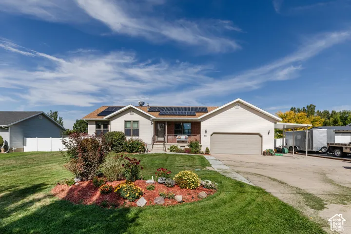 Single-story residence featuring solar panels, an attached two-car garage, a covered front porch, and a carport