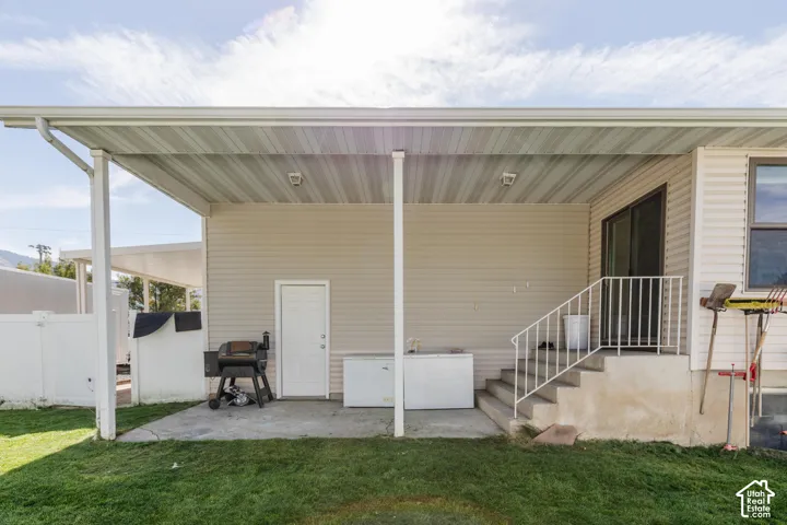 Covered patio with vinyl siding, concrete steps, and a white railing