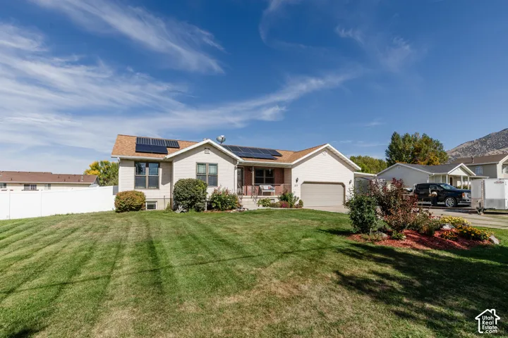 Single-story exterior with a two-car garage, solar panels, and a front yard featuring established landscaping