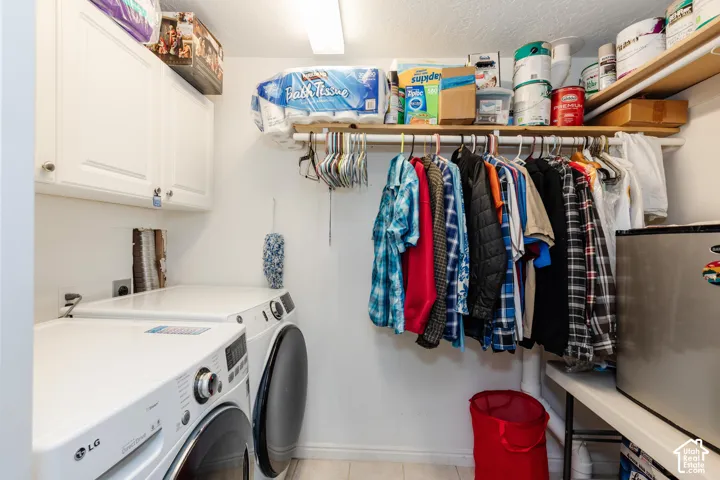 Laundry area featuring front-loading machines, upper white cabinetry, and wall-mounted shelving