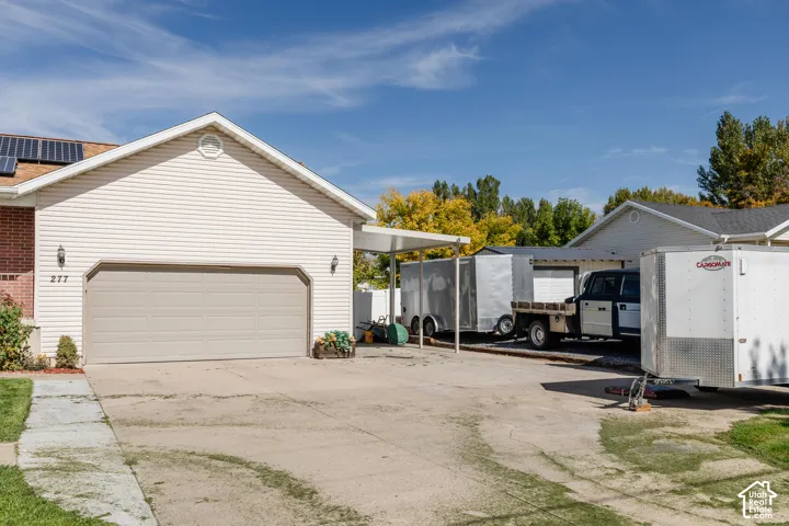 Attached two-car garage with a light-colored sectional door, solar panels on the roof, and a side brick facade