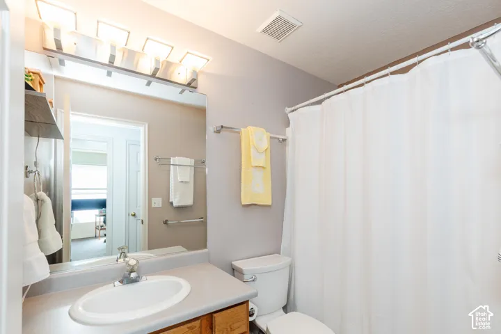 Vanity with integrated sink, wood-finish cabinetry, and overhead lighting