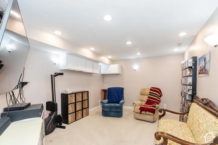 Recessed ceiling lighting, wall-mounted sconces, and white overhead cabinetry
