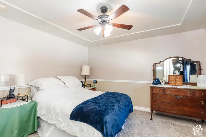 Tray ceiling with a ceiling fan, two-tone wall paint, and carpet flooring