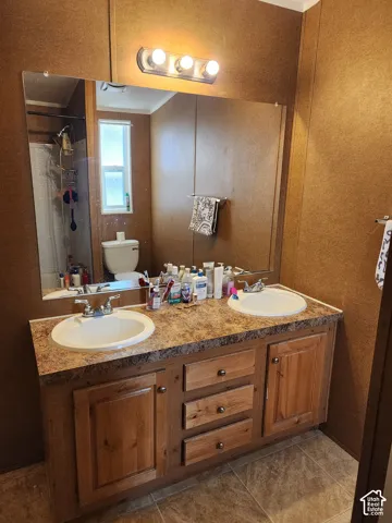Dual vanity with laminate countertop, two integrated sinks, and wood-finish cabinetry