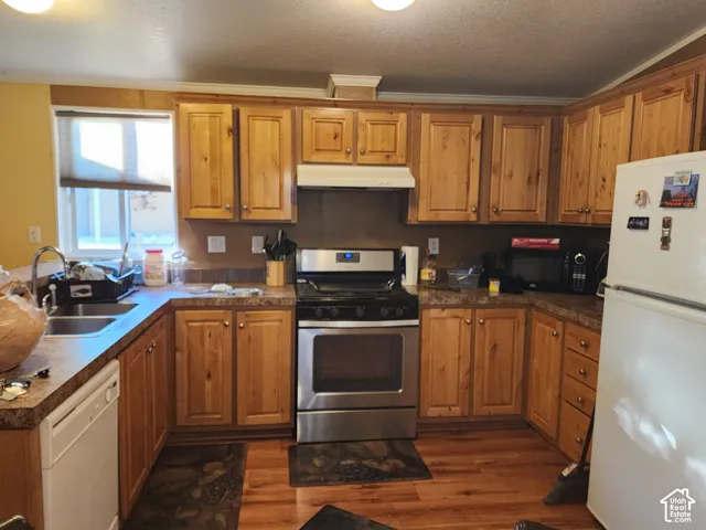 Kitchen featuring wood-finish cabinetry, stainless steel range, and a double-basin sink