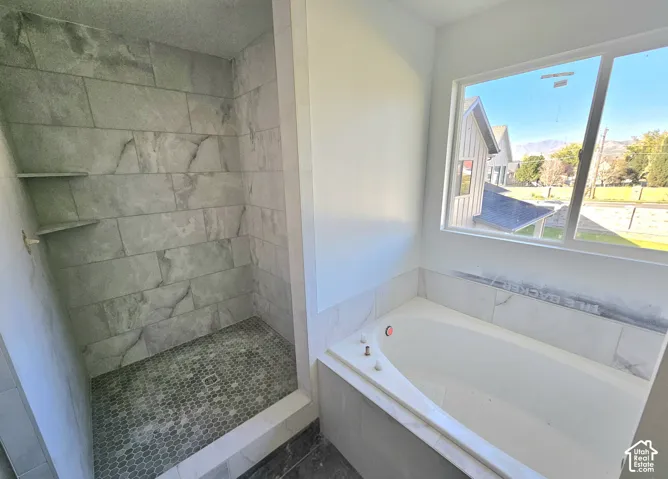 Walk-in shower with tiled walls and hex tile flooring, featuring two built-in shelves